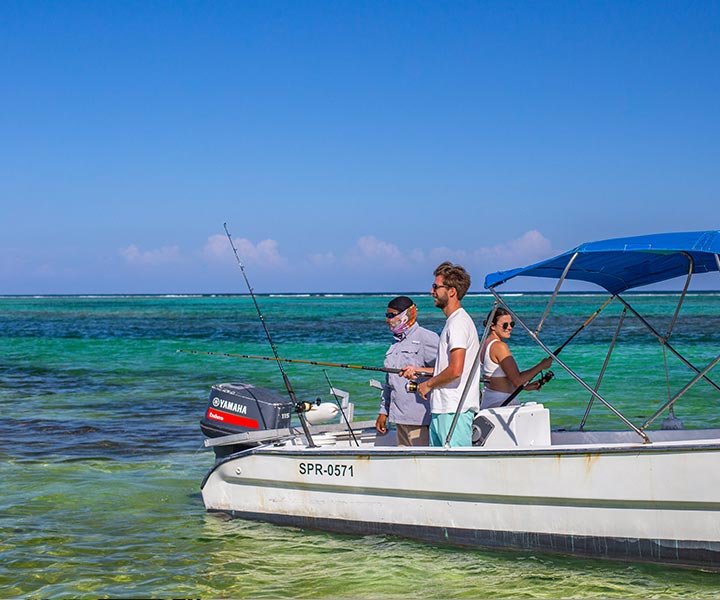 Three people fishing on a small boat in clear turquoise water